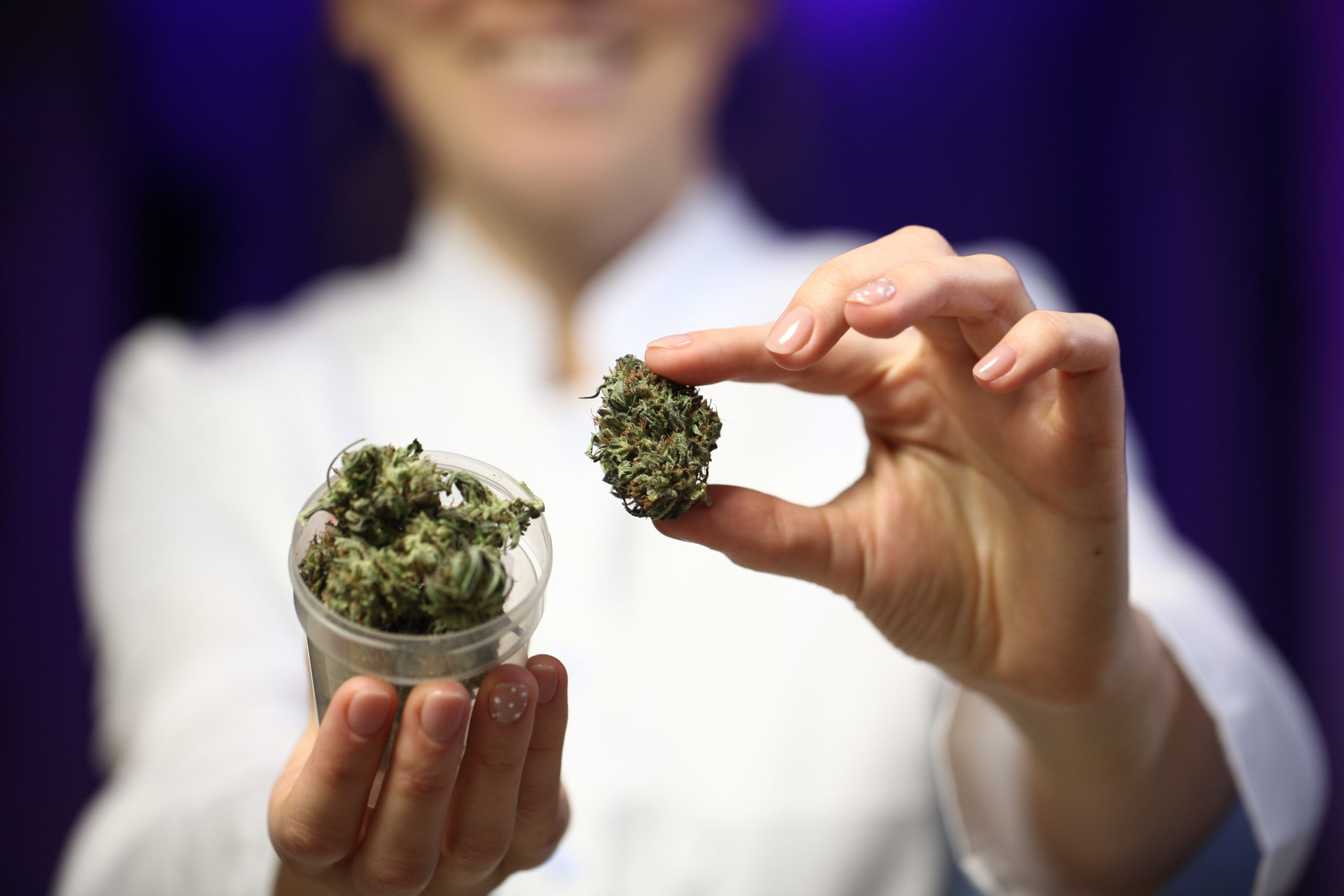 woman holding marijuana bud and glass jar