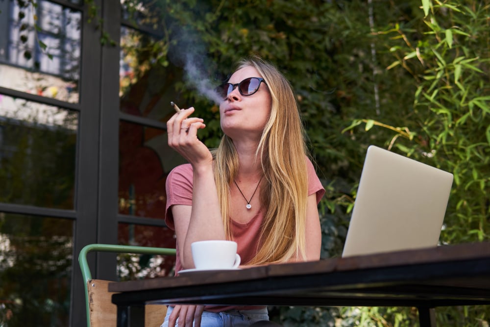 woman smoking a joint at an outdoor cafe