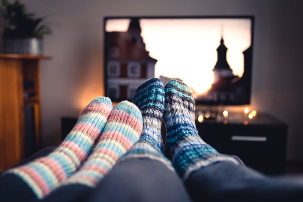 two pairs of feet with socks infront of tv