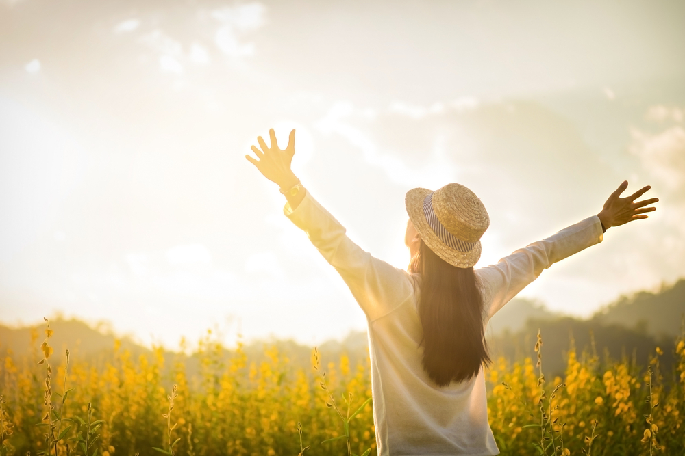 woman in a field open arms to the sunshine