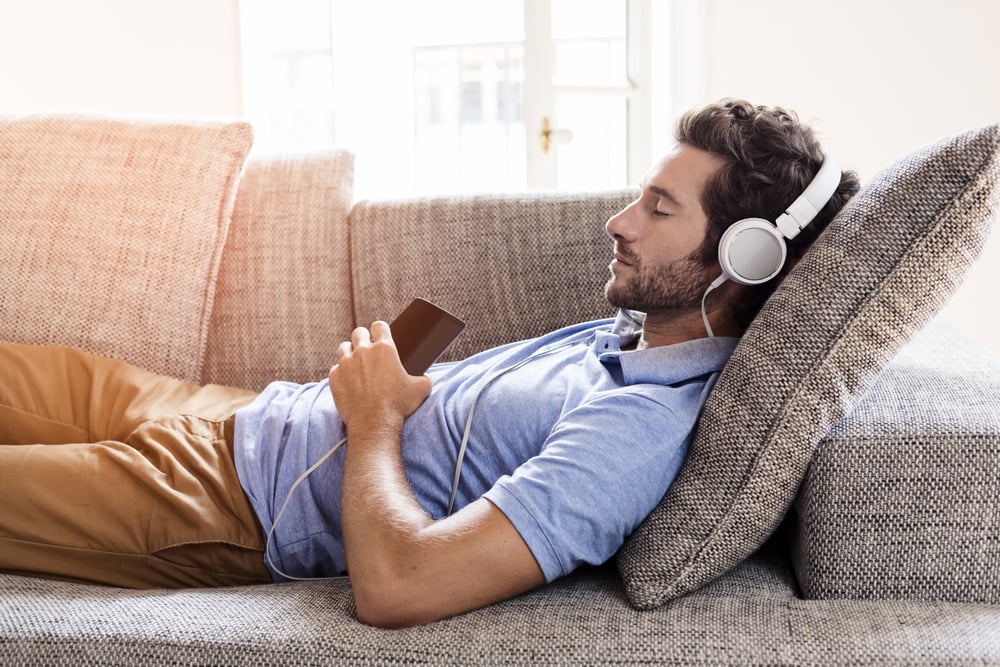 Man at home on sofa listening a music with a smartphone