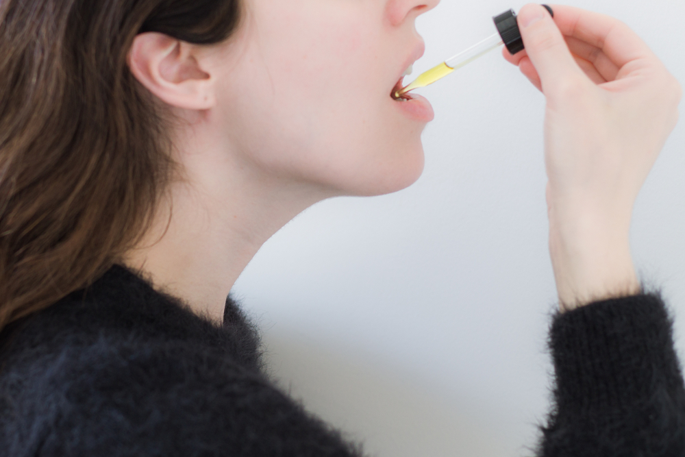 woman taking tincture with an eyedrop