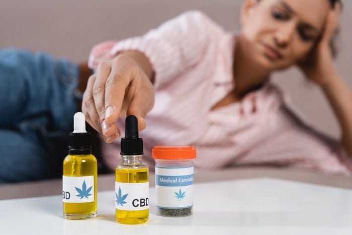 woman reaching for cannabis oil bottle