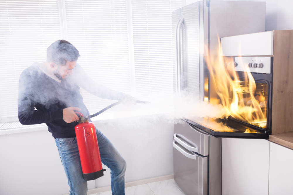 man putting out oven fire in the kitchen